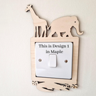 A wooden light switch with a giraffe and elephant silhouette on top, and the text "This is Design 1 in Maple" on the switch.