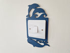 A light switch with a decorative blue frame featuring a playful design of two dolphins jumping in the air.