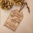 Christmas gift tags with personalized messages, surrounded by holly leaves and pine cones on a beige background.