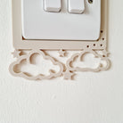 a light switch with a decorative frame featuring clouds and stars.