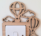 A wooden light switch with a decorative design featuring hot air balloons and clouds.