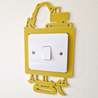A yellow and white light switch with a playful construction vehicle-shaped frame.