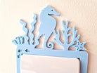 A blue seahorse-shaped light switch on a wall.