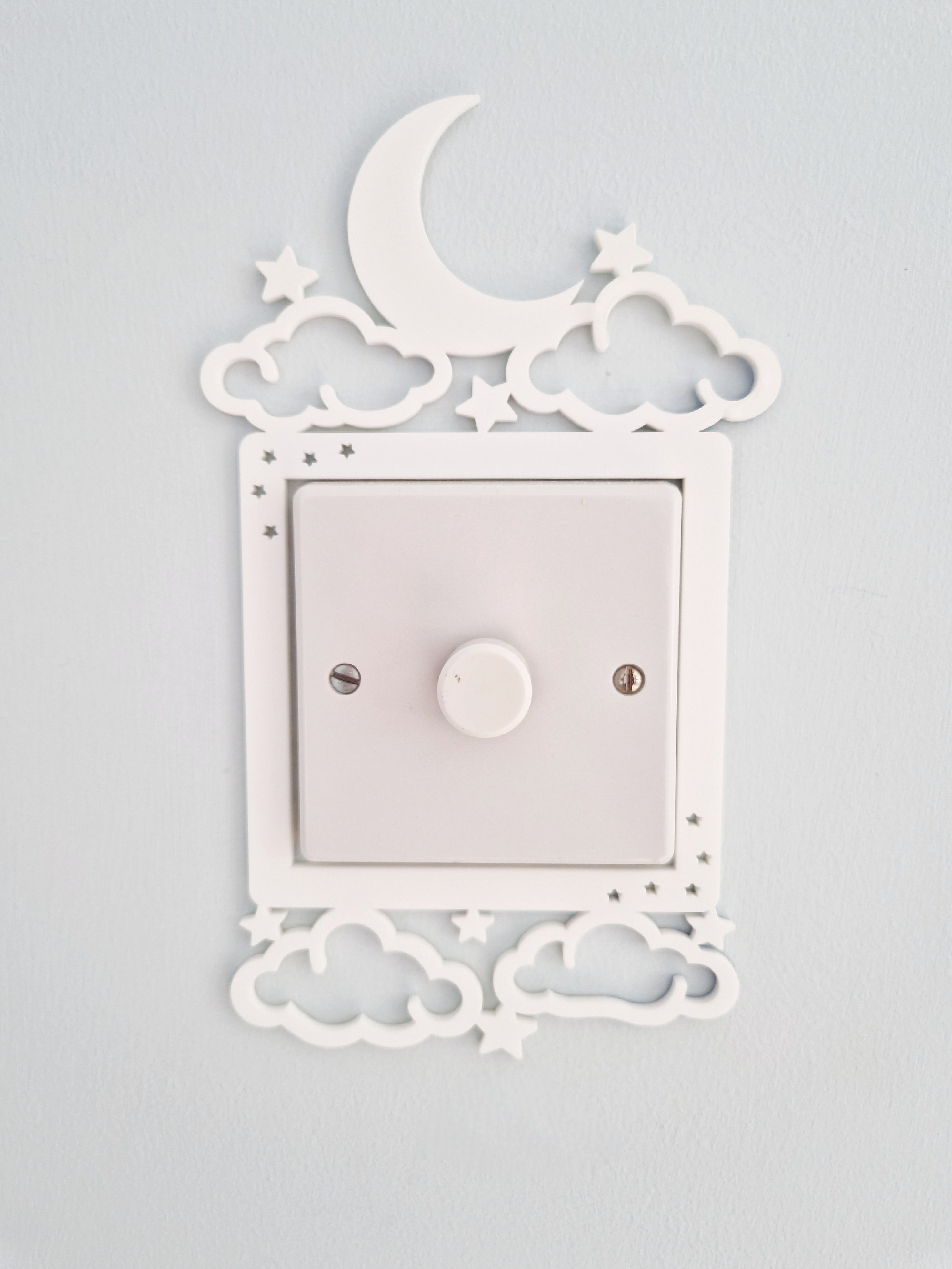 a white light switch with a moon and star decoration above it, mounted on a wall.