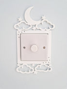 a white light switch with a moon and star decoration above it, mounted on a wall.