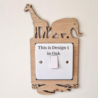 A wooden light switch with a giraffe and elephant silhouette on top, and a label that reads "This is Design 1 in Oak".