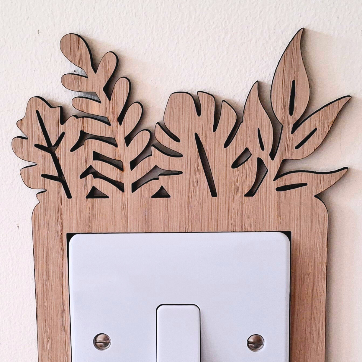 A wooden light switch with a leaf-shaped design on the top and bottom edges, mounted on a white wall.