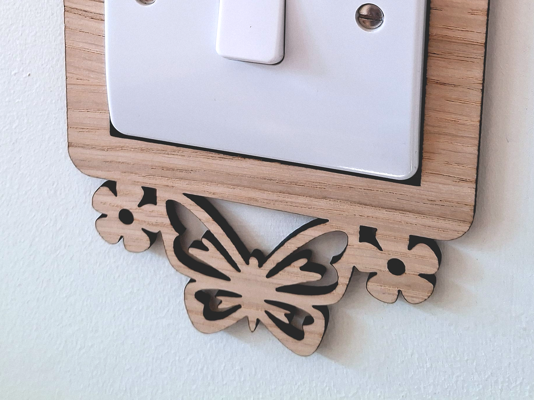 A wooden butterfly-shaped light switch cover is mounted on a wall.