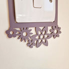 a purple floral-patterned light switch plate mounted on a wall.