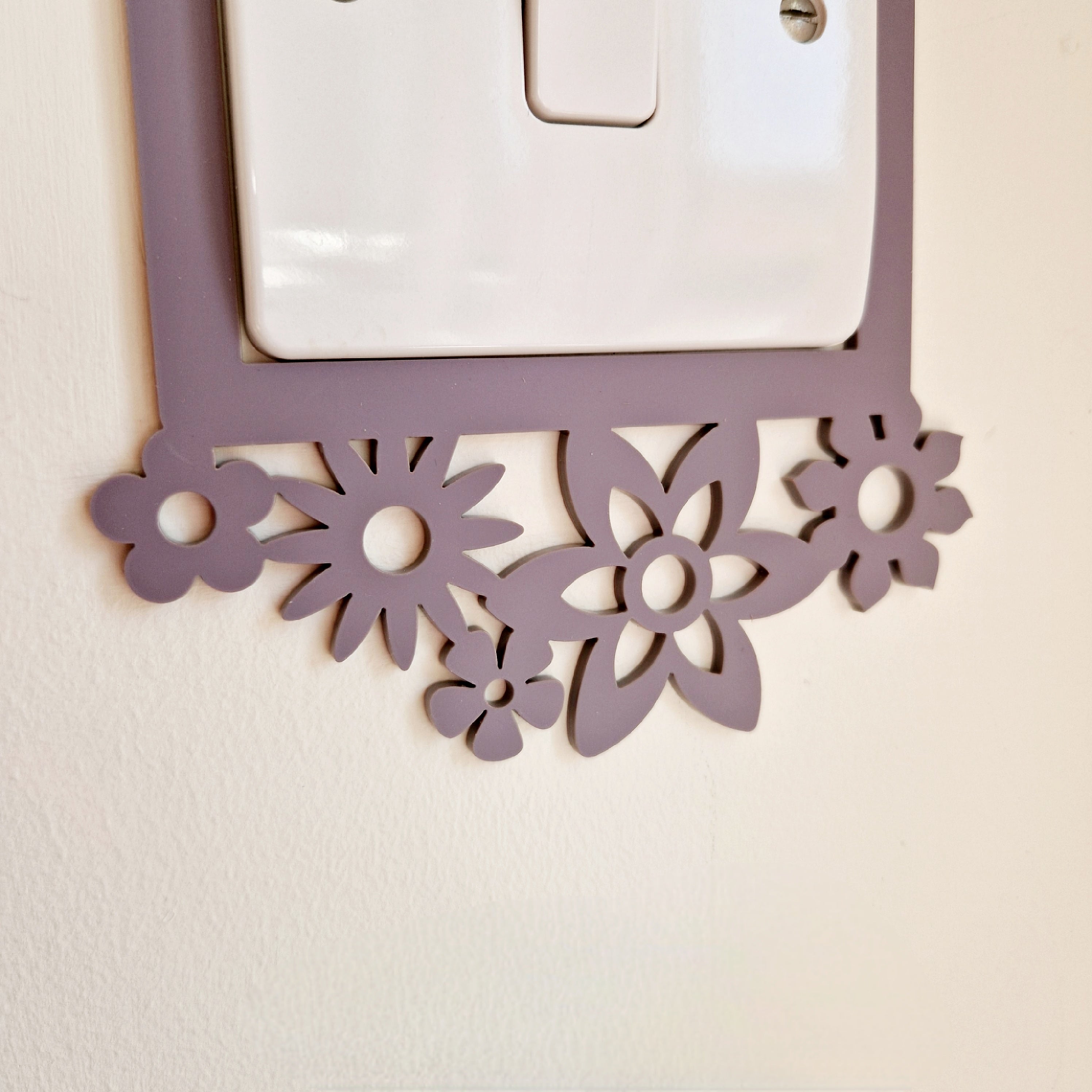 a purple floral-patterned light switch plate mounted on a wall.