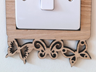A wooden light switch with a butterfly-shaped frame is mounted on a white wall.