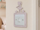 Decorative pink light switch cover with a dancing ballerina design in a child's room.