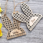 Wooden bunny ear-shaped tags with engraved names next to yellow daffodils on a wooden surface