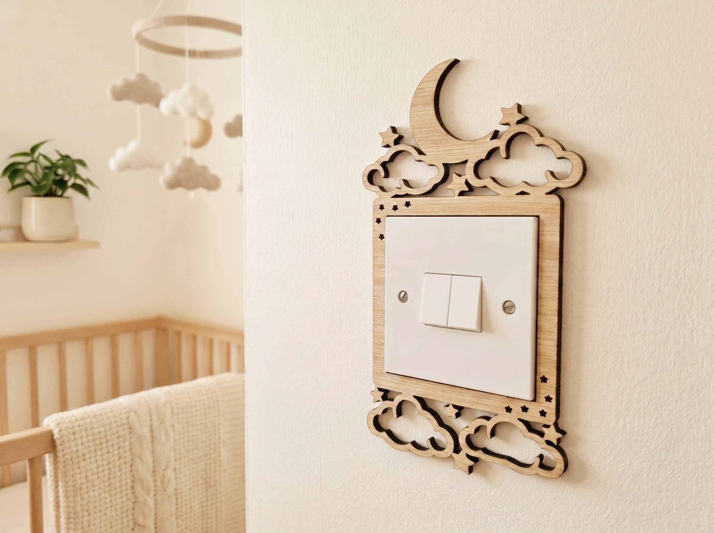 Decorative light switch cover with cloud moon and stars design in wood, on a wall in a nursery.
