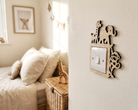A wooden animal silhouette light switch cover mounted on a white wall in a softly lit bedroom. The cover features cutout shapes of a giraffe, elephant, and monkey around a white switch plate.