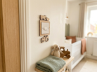 Wooden light surround with farmyard animals and a tractor on the wall in a Children's room with wooden toys and a teddy bear on a shelf.