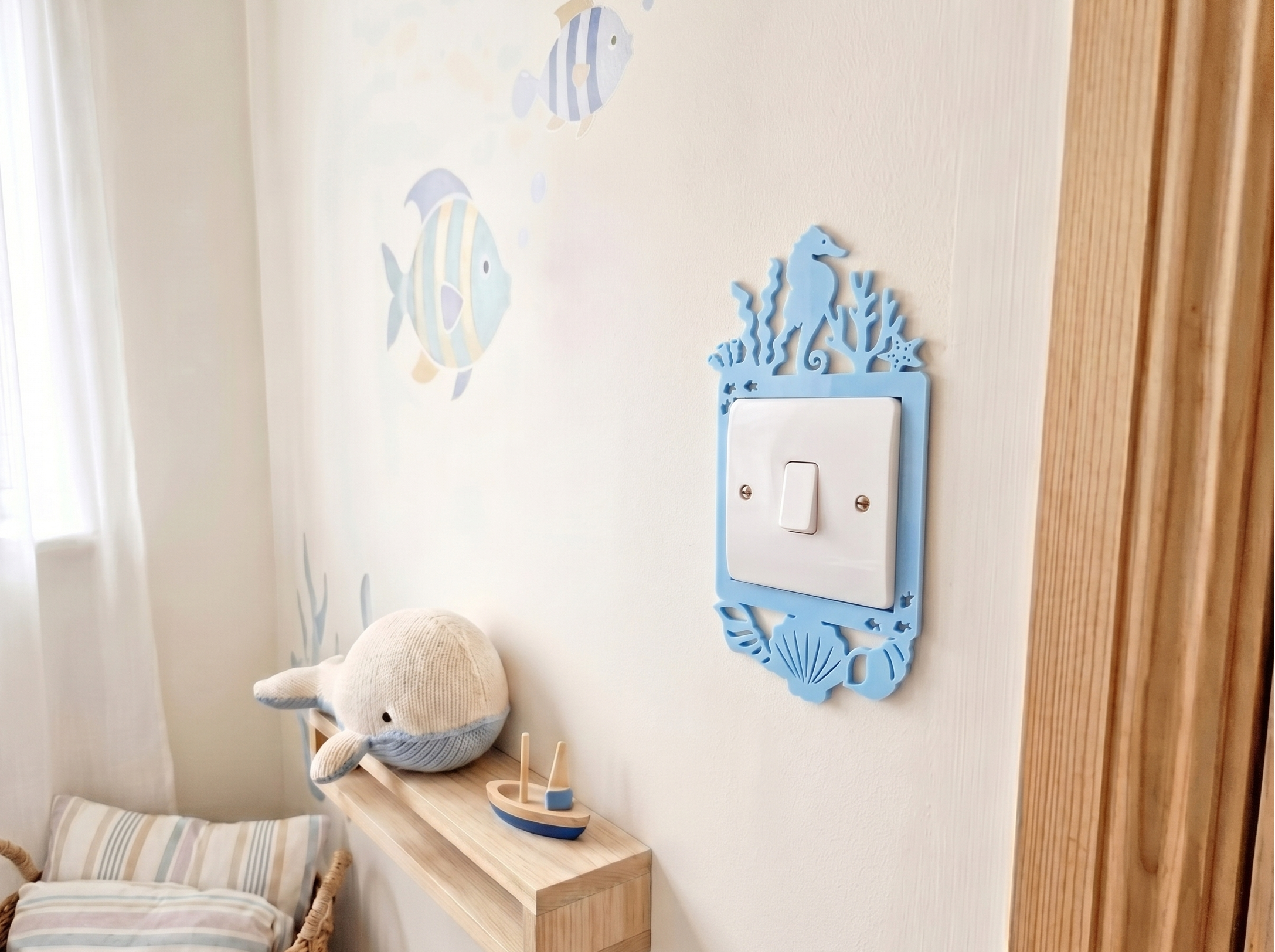 Children's room with an ocean themed decorative light switch cover, plush toy, and wall stickers.