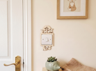 Decorative wooden wall switch plate with woodland forest animal design and underneath, a succulent plant and folded blanket on a bench.