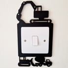 A wall-mounted light switch with a black and white design featuring construction vehicles and equipment.