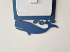 A light switch with a blue whale decoration on the plate.