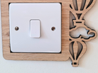 A wooden light switch with a decorative design featuring hot air balloons and clouds.
