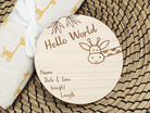 A wooden baby name card with a giraffe design, placed on a woven placemat.