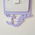 A purple mermaid-shaped light switch cover is attached to a wall, with a white light switch below it.