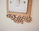 a wooden switch plate with a decorative floral design on it, mounted on a wall.