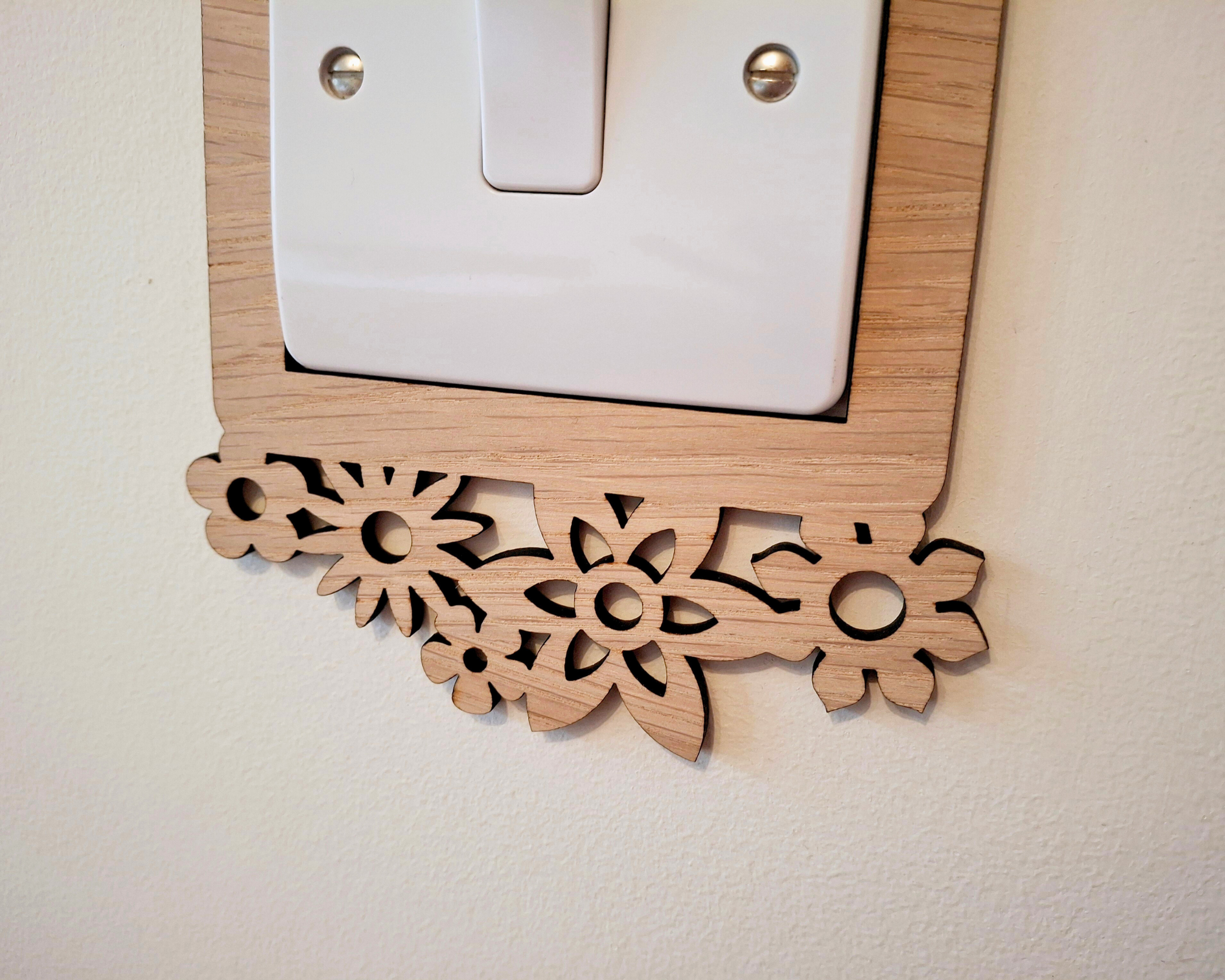 a wooden switch plate with a decorative floral design on it, mounted on a wall.